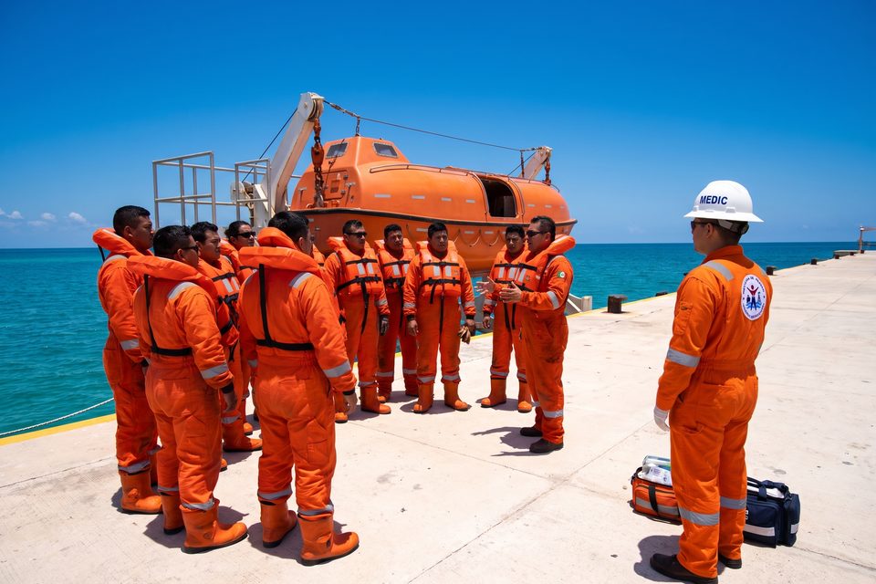 Medic MEDLAB acompaña una práctica de supervivencia STCW junto al bote salvavidas en el muelle de entrenamiento